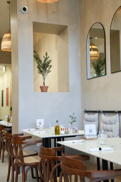 Cozy dining nook with arched mirrors and potted olive tree at Eggstatic Waterdown