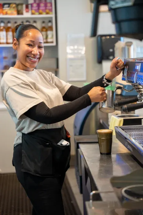 Smiling barista steaming milk for a latte at Eggstatic Scarborough