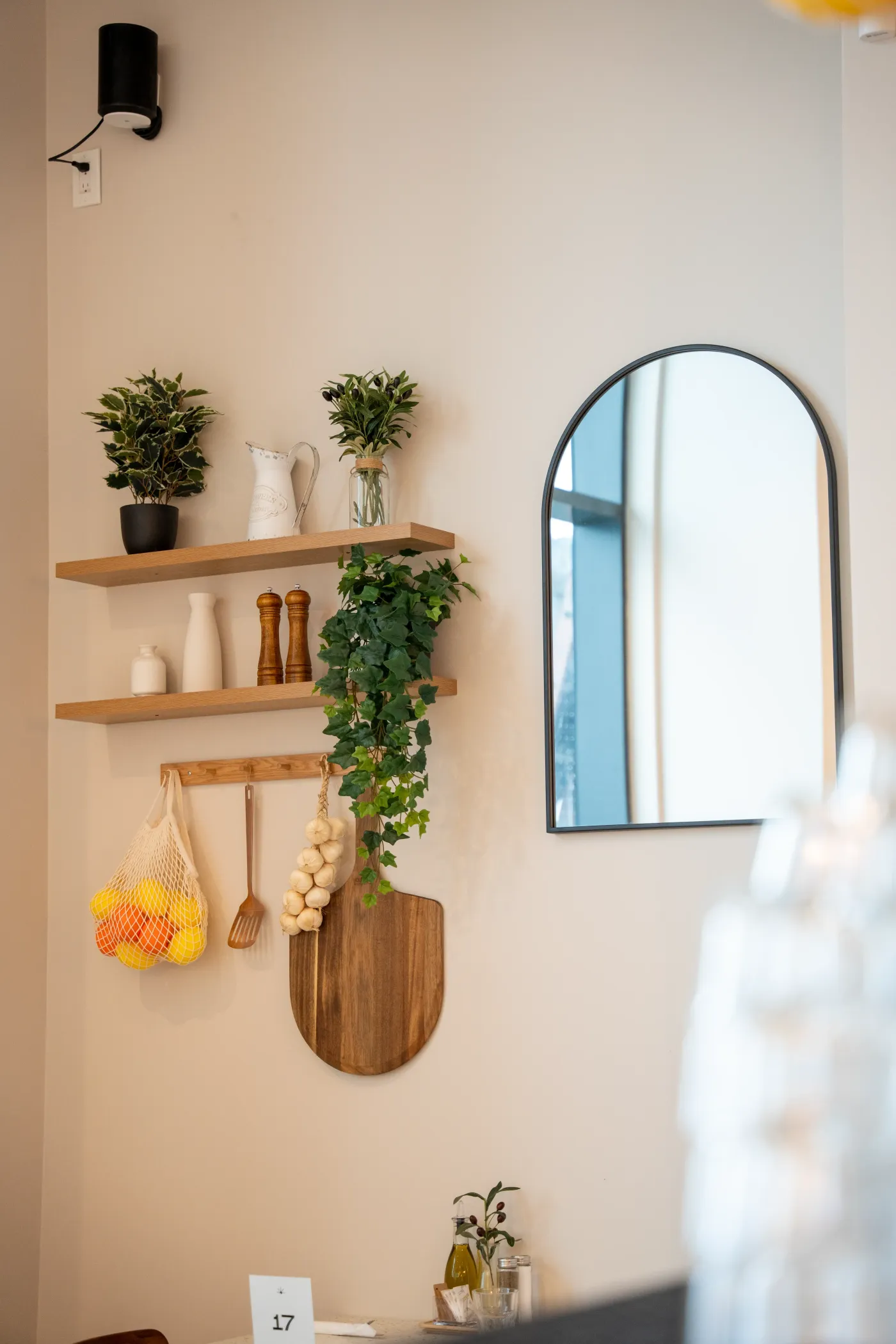 Eggstatic wall shelves with plants, an arched mirror and a net bag of oranges