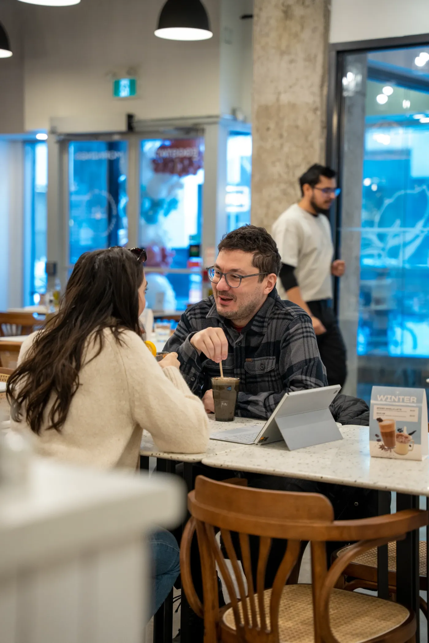 Guests chatting over iced coffee at a marble table inside Eggstatic Downtown Toronto