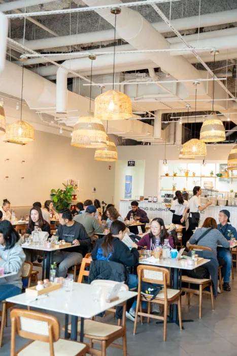 Busy brunch service at Eggstatic Scarborough with families dining under rattan pendants