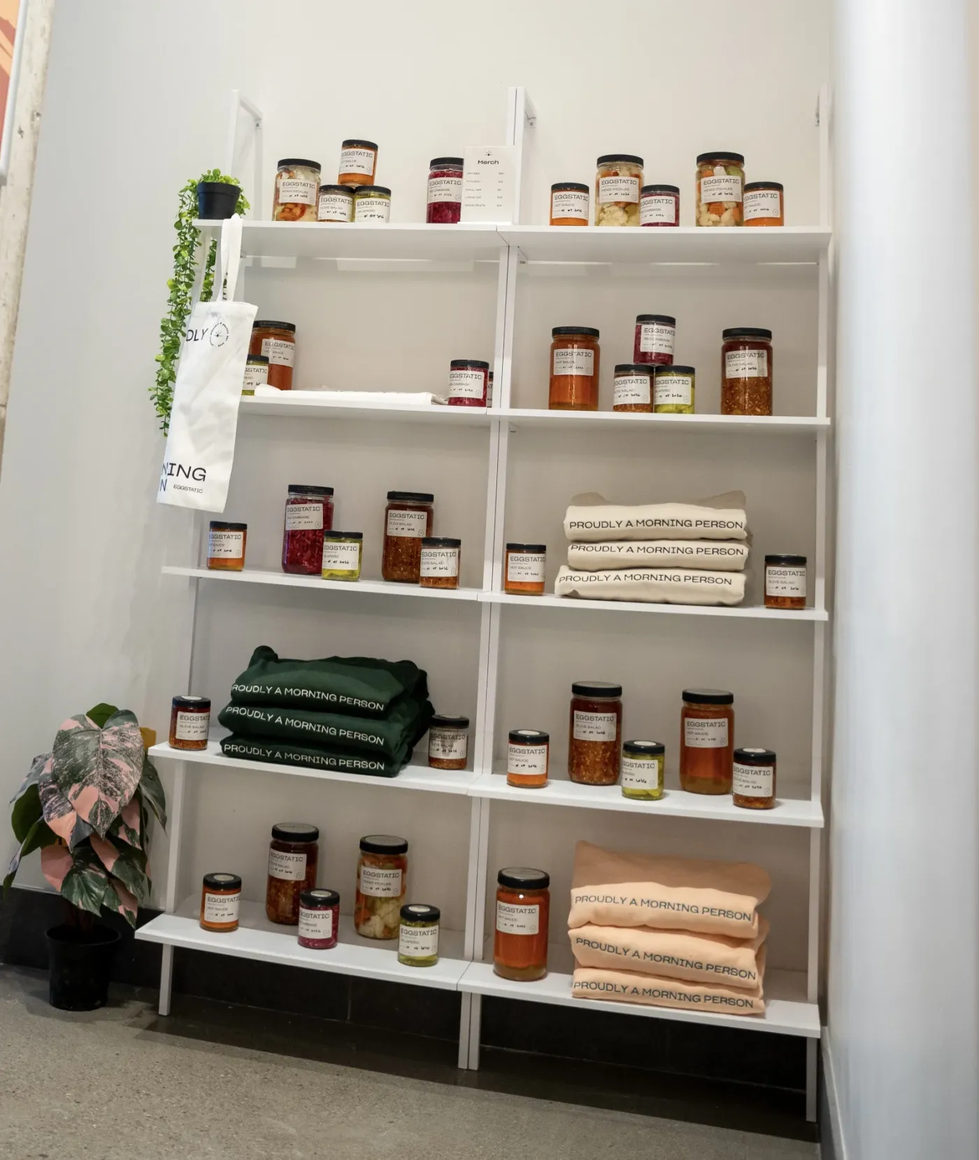 Retail shelf of house-made preserves and "Proudly a Morning Person" merch at Eggstatic Downtown Toronto