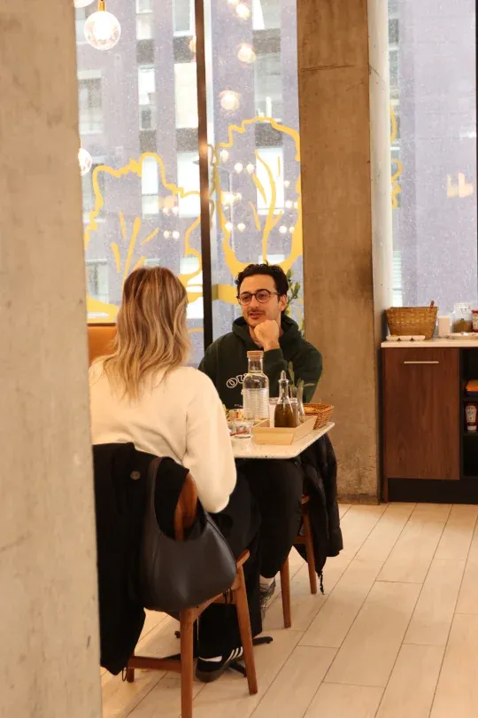 Couple enjoying brunch by the yellow window mural at Eggstatic Montreal in Griffintown