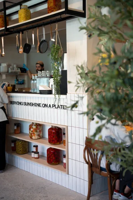 Barista at the service counter beneath the "Serving Sunshine on a Plate" tagline at Eggstatic Oakville