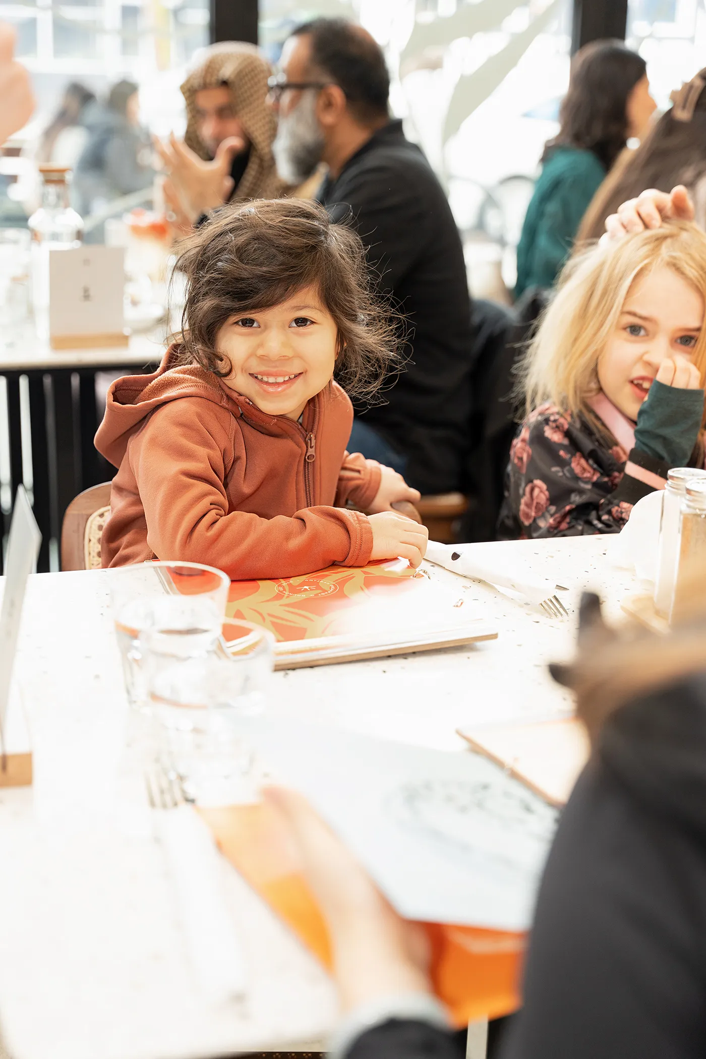 Child smiling at a family brunch table at Eggstatic