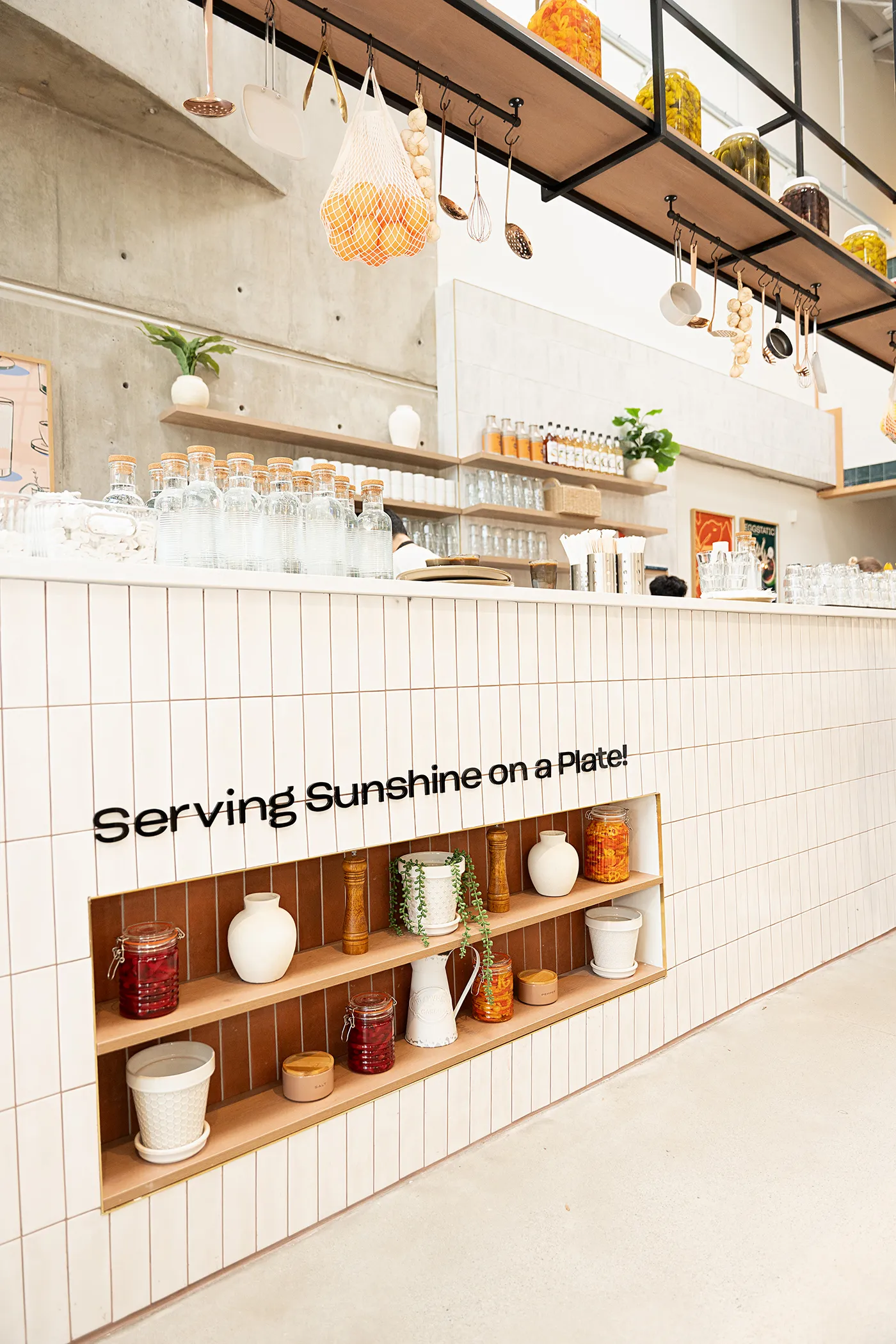 Eggstatic counter with “Serving Sunshine on a Plate” wall lettering and shelves of preserves