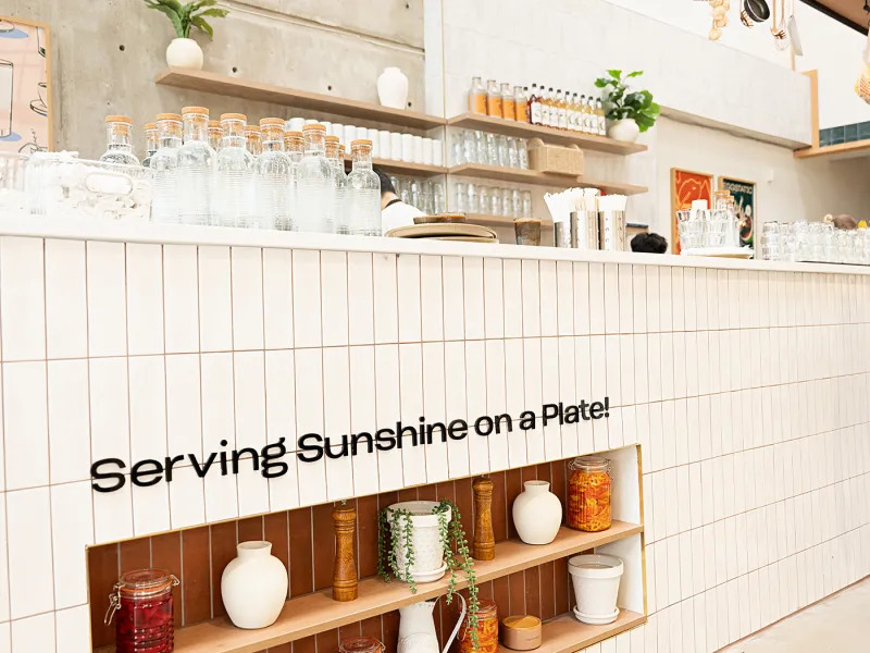 Eggstatic counter with “Serving Sunshine on a Plate” wall lettering and shelves of preserves